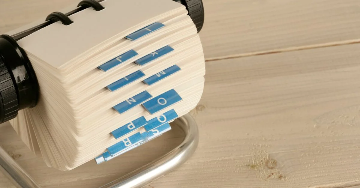 Un gros plan d'un Rolodex traditionnel avec des onglets alphabétiques sur un bureau en bois.